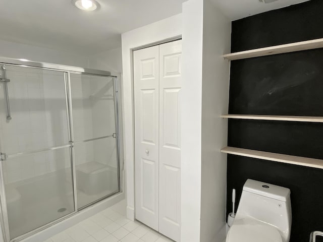 bathroom featuring toilet, tile patterned floors, a shower stall, and a closet