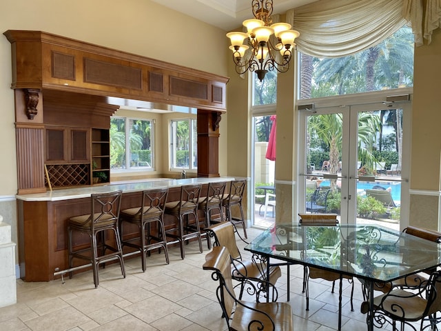 dining area featuring stone finish floor, french doors, and a chandelier
