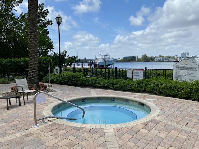view of pool featuring a water view, fence, and a community hot tub