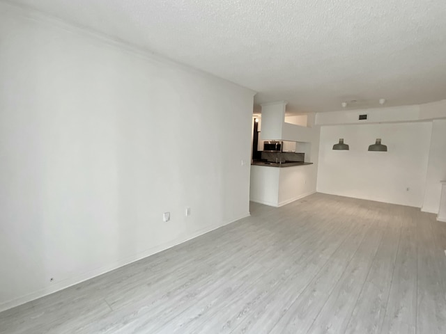 unfurnished living room featuring a textured ceiling and light wood-style floors
