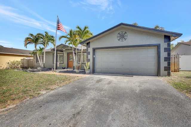ranch-style home featuring fence, a garage, aphalt driveway, and stucco siding