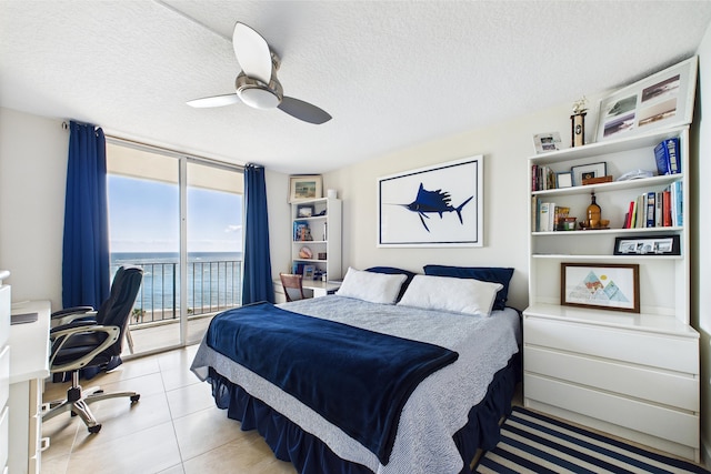 bedroom with ceiling fan, a textured ceiling, expansive windows, a water view, and access to outside