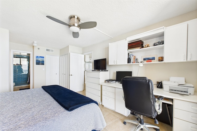 bedroom with built in study area, light tile patterned floors, multiple windows, and visible vents