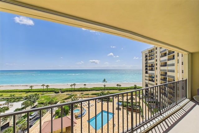balcony with a water view and a view of the beach