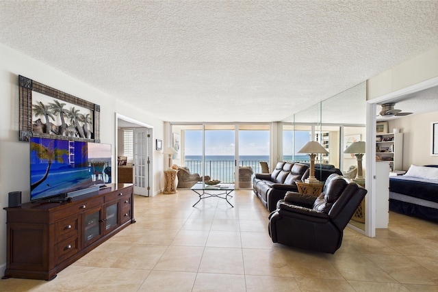 living area featuring light tile patterned floors, a wall of windows, a textured ceiling, and ceiling fan