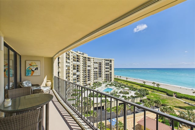 balcony with a water view and a view of the beach