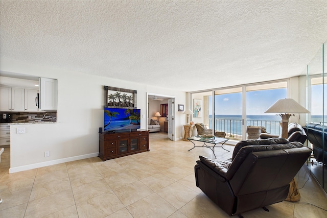 living area with light tile patterned flooring, a textured ceiling, floor to ceiling windows, and baseboards