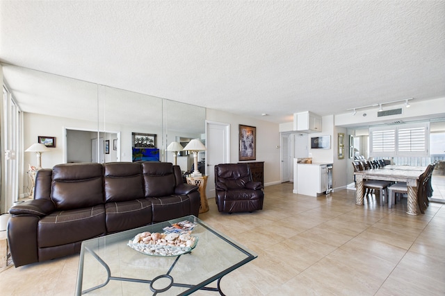 living room featuring visible vents, baseboards, a textured ceiling, and light tile patterned floors