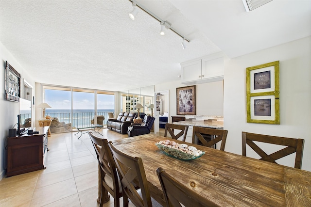 dining space featuring expansive windows, rail lighting, a textured ceiling, and light tile patterned floors
