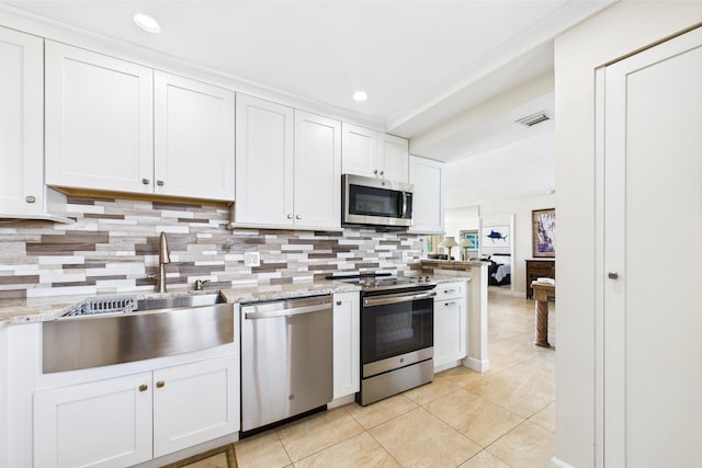 kitchen with decorative backsplash, a sink, light tile patterned floors, stainless steel appliances, and white cabinetry