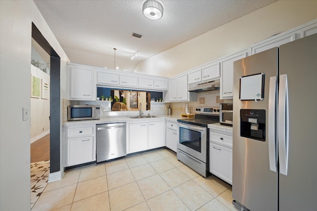 kitchen with a sink, stainless steel appliances, under cabinet range hood, white cabinetry, and lofted ceiling