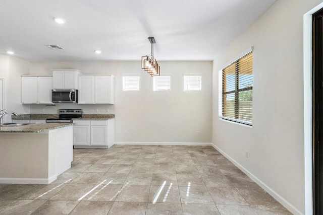 6056 NW Regent St, Port Saint Lucie, FL 34983 - kitchen featuring visible vents, white cabinets, light stone counters, a sink, and stainless steel appliances