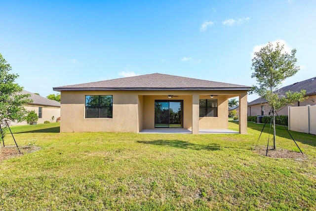 6056 NW Regent St, Port Saint Lucie, FL 34983 - back of property with a ceiling fan, a lawn, fence, a patio, and stucco siding