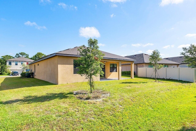 6056 NW Regent St, Port Saint Lucie, FL 34983 - back of house with stucco siding, a lawn, fence, and a patio area