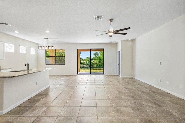 6056 NW Regent St, Port Saint Lucie, FL 34983 - unfurnished living room with visible vents, a sink, baseboards, and ceiling fan