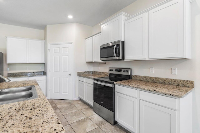 6056 NW Regent St, Port Saint Lucie, FL 34983 - kitchen with stainless steel appliances, recessed lighting, white cabinetry, and a sink