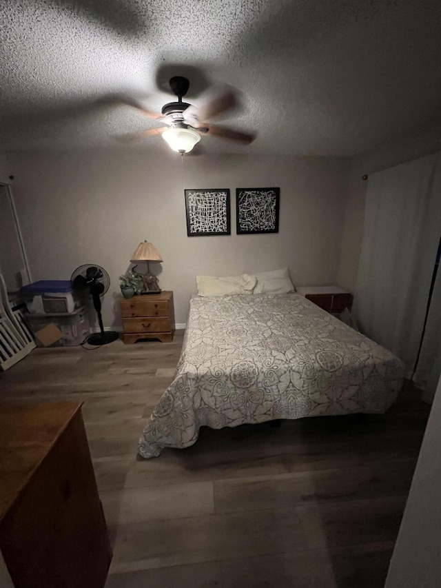 bedroom with a textured ceiling, a ceiling fan, and wood finished floors