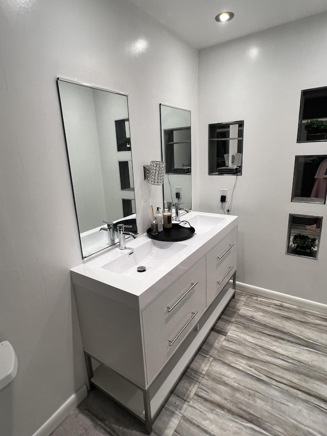 bathroom featuring baseboards, double vanity, and a sink