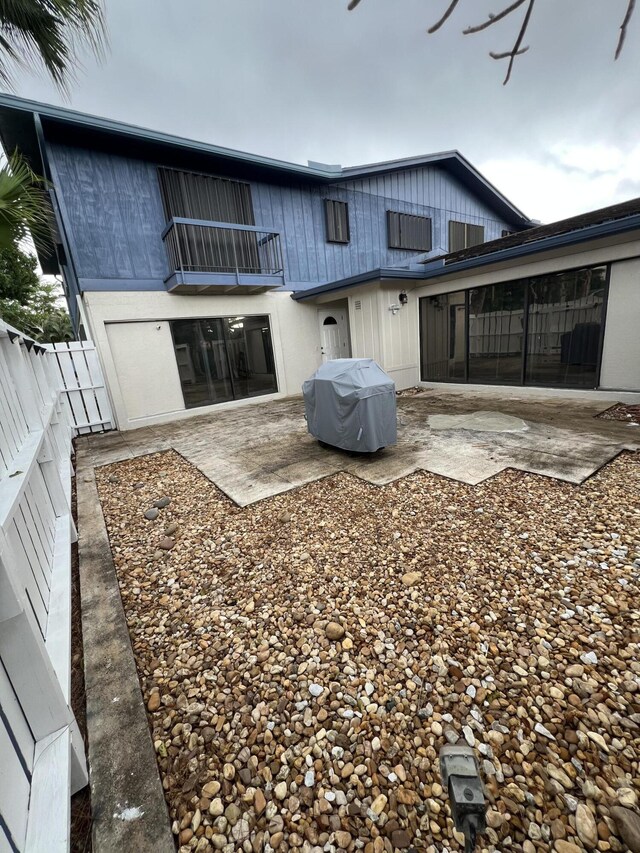 back of property featuring a balcony, a fenced backyard, and a patio area