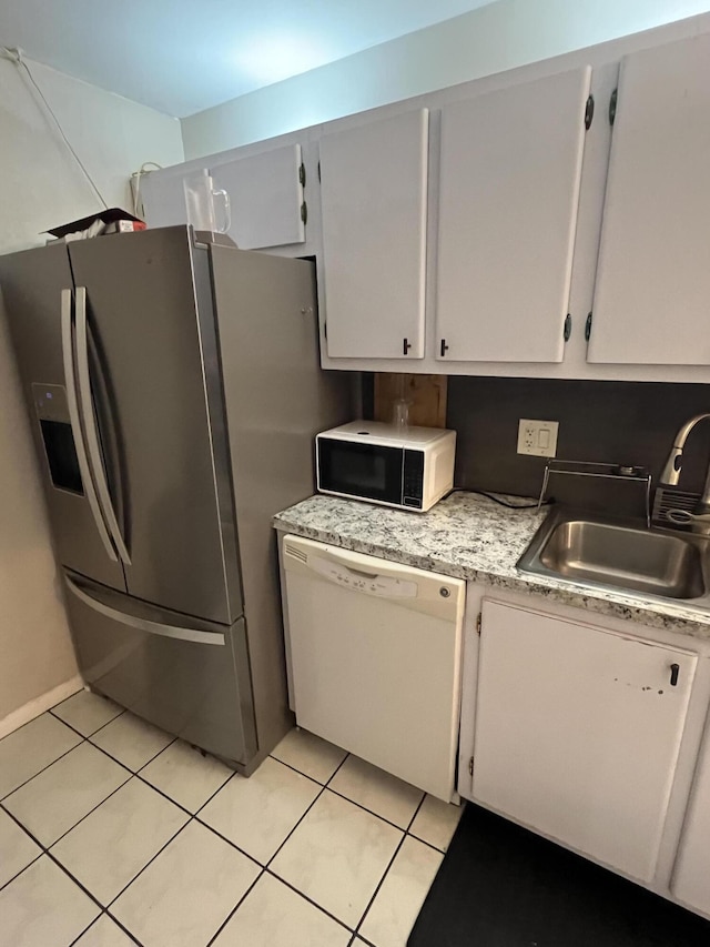 kitchen with a sink, light tile patterned floors, stainless steel fridge, white dishwasher, and black microwave