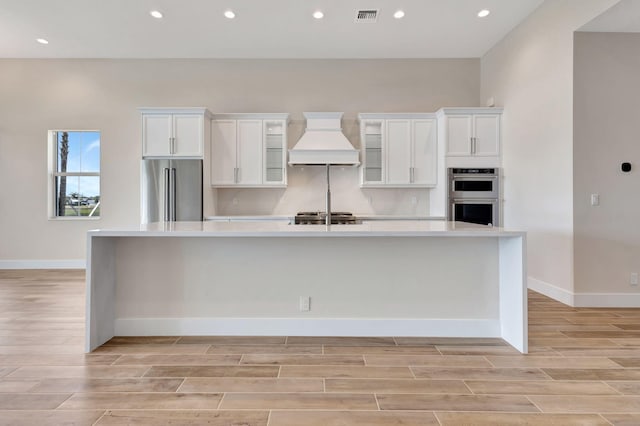 kitchen with stainless steel appliances, visible vents, custom exhaust hood, and light wood-style floors