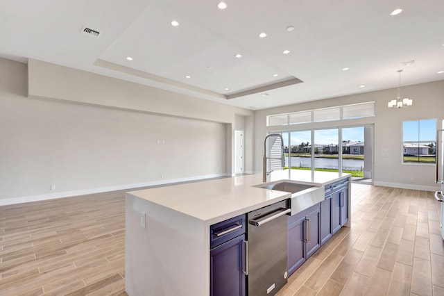 kitchen featuring a sink, open floor plan, baseboards, stainless steel dishwasher, and a tray ceiling