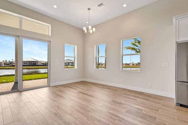unfurnished dining area featuring visible vents, a water view, a chandelier, and a wealth of natural light