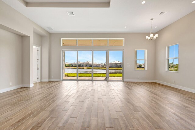 unfurnished living room featuring an inviting chandelier, a wealth of natural light, and wood finished floors