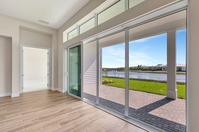 doorway featuring a water view, baseboards, visible vents, and wood finished floors