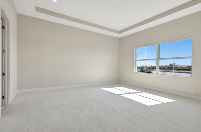 empty room with carpet floors, recessed lighting, baseboards, and a raised ceiling