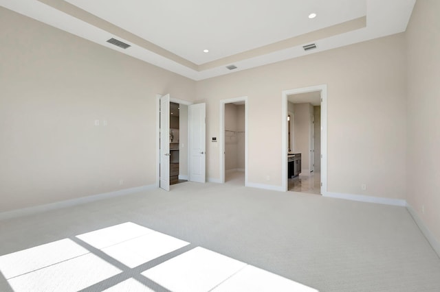 unfurnished bedroom featuring light colored carpet, baseboards, visible vents, and a spacious closet