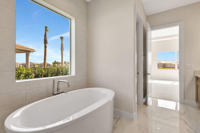 full bathroom with baseboards, a freestanding bath, marble finish floor, and vanity