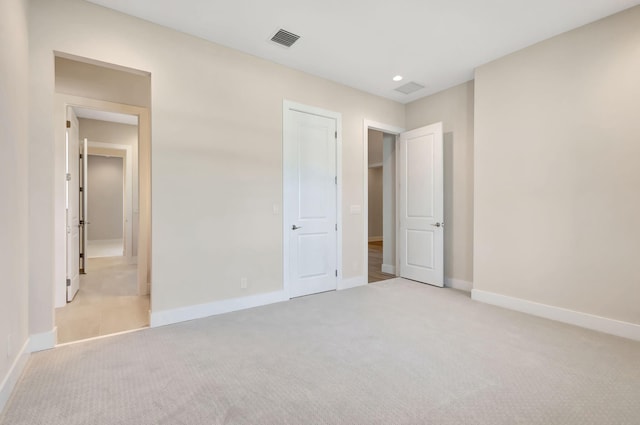 unfurnished bedroom with baseboards, light colored carpet, recessed lighting, and visible vents