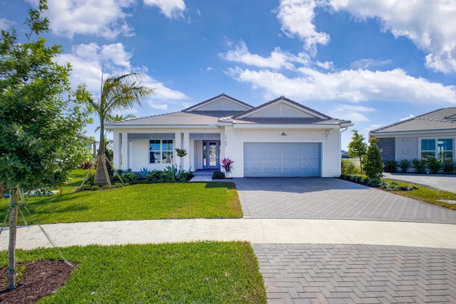 ranch-style house featuring a front yard, decorative driveway, french doors, board and batten siding, and an attached garage