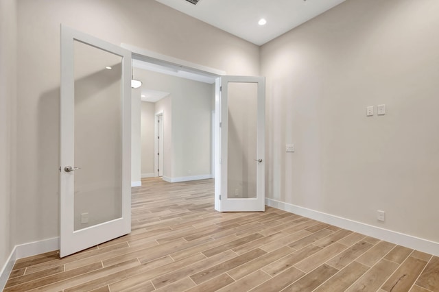 spare room featuring baseboards, french doors, and light wood-style floors
