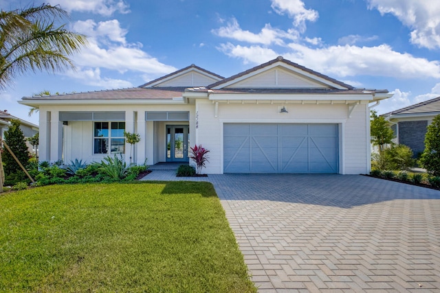 single story home featuring decorative driveway, french doors, a front yard, and a garage