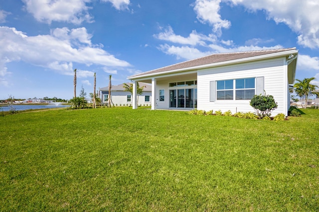 rear view of property with a water view and a yard