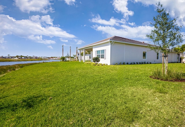 view of side of home with a yard and a water view