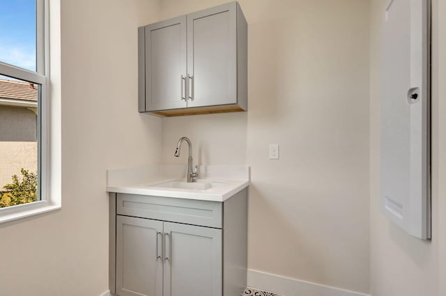 bar featuring baseboards and a sink