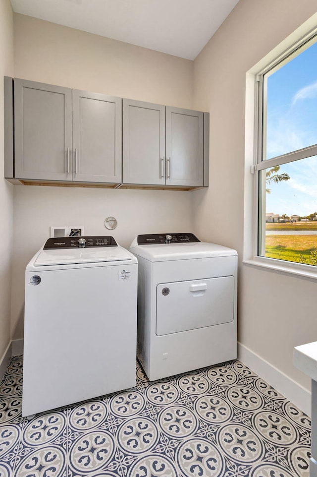 laundry room featuring washer and dryer, light tile patterned flooring, baseboards, and cabinet space