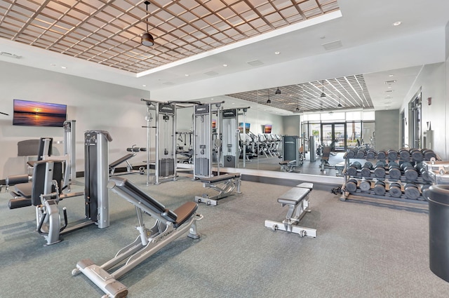 exercise room with a raised ceiling, recessed lighting, and visible vents