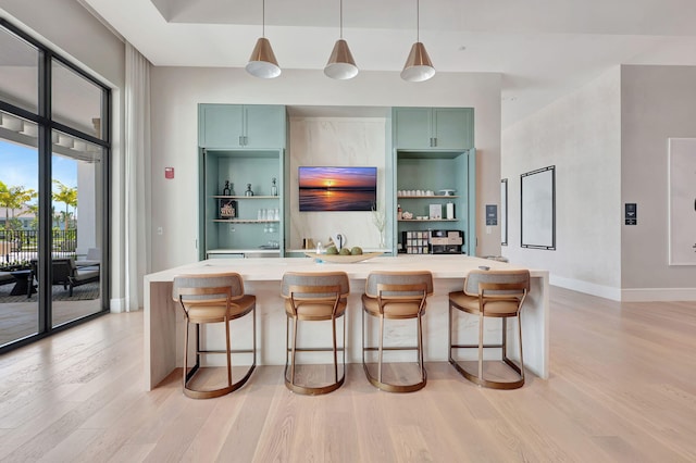 bar featuring baseboards, pendant lighting, and light wood-style flooring