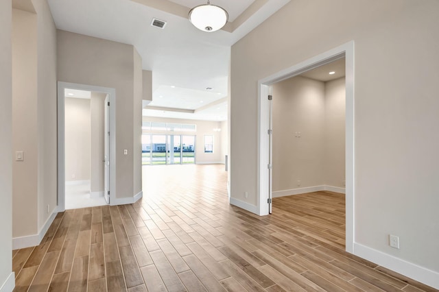 interior space with visible vents, wood finished floors, a raised ceiling, baseboards, and recessed lighting