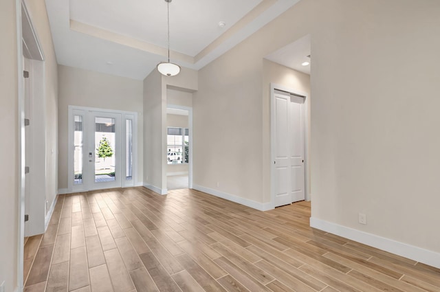 entrance foyer featuring baseboards, light wood-style flooring, and a high ceiling