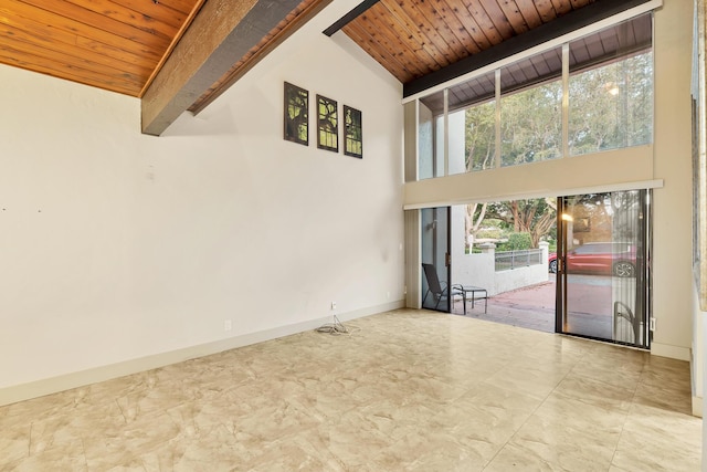 empty room with baseboards, beam ceiling, high vaulted ceiling, and wood ceiling