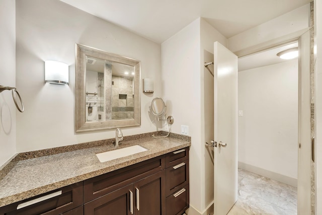 full bath featuring marble finish floor, vanity, and a shower