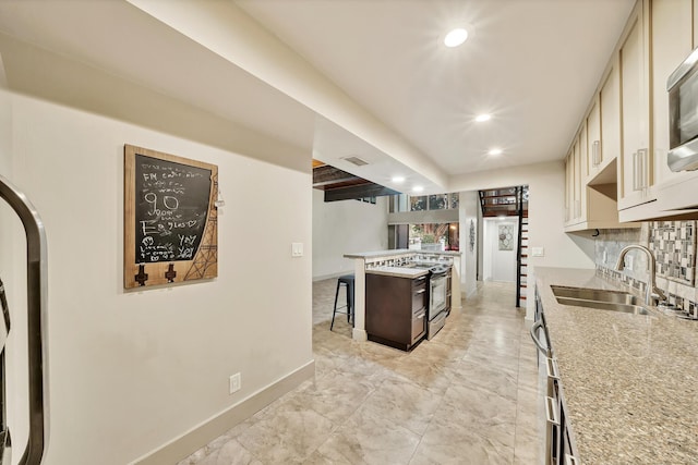 kitchen featuring a sink, a breakfast bar, recessed lighting, electric range, and baseboards