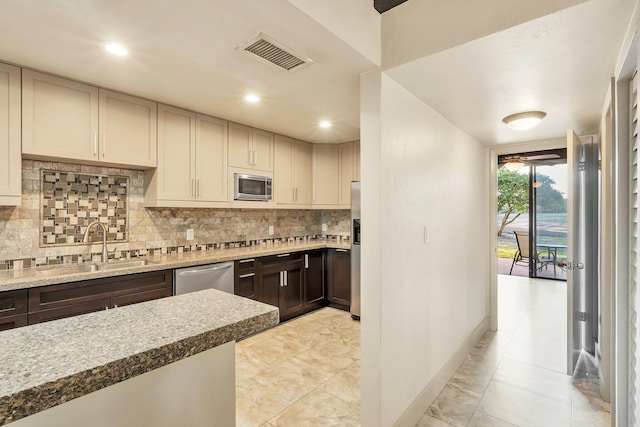 kitchen with visible vents, a sink, dark brown cabinetry, backsplash, and stainless steel appliances