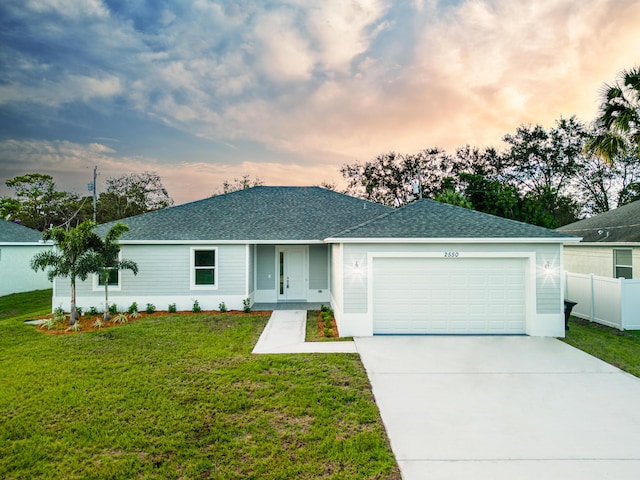 ranch-style home featuring a lawn, an attached garage, concrete driveway, and roof with shingles