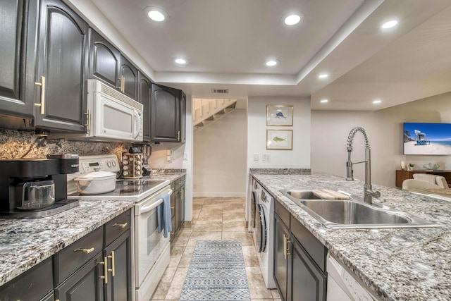 kitchen featuring a sink, white appliances, tasteful backsplash, visible vents, and a kitchen bar